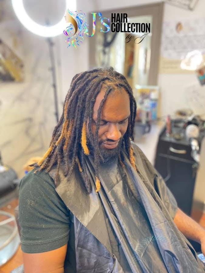 man in a barbersho with dreads and blonde highlights